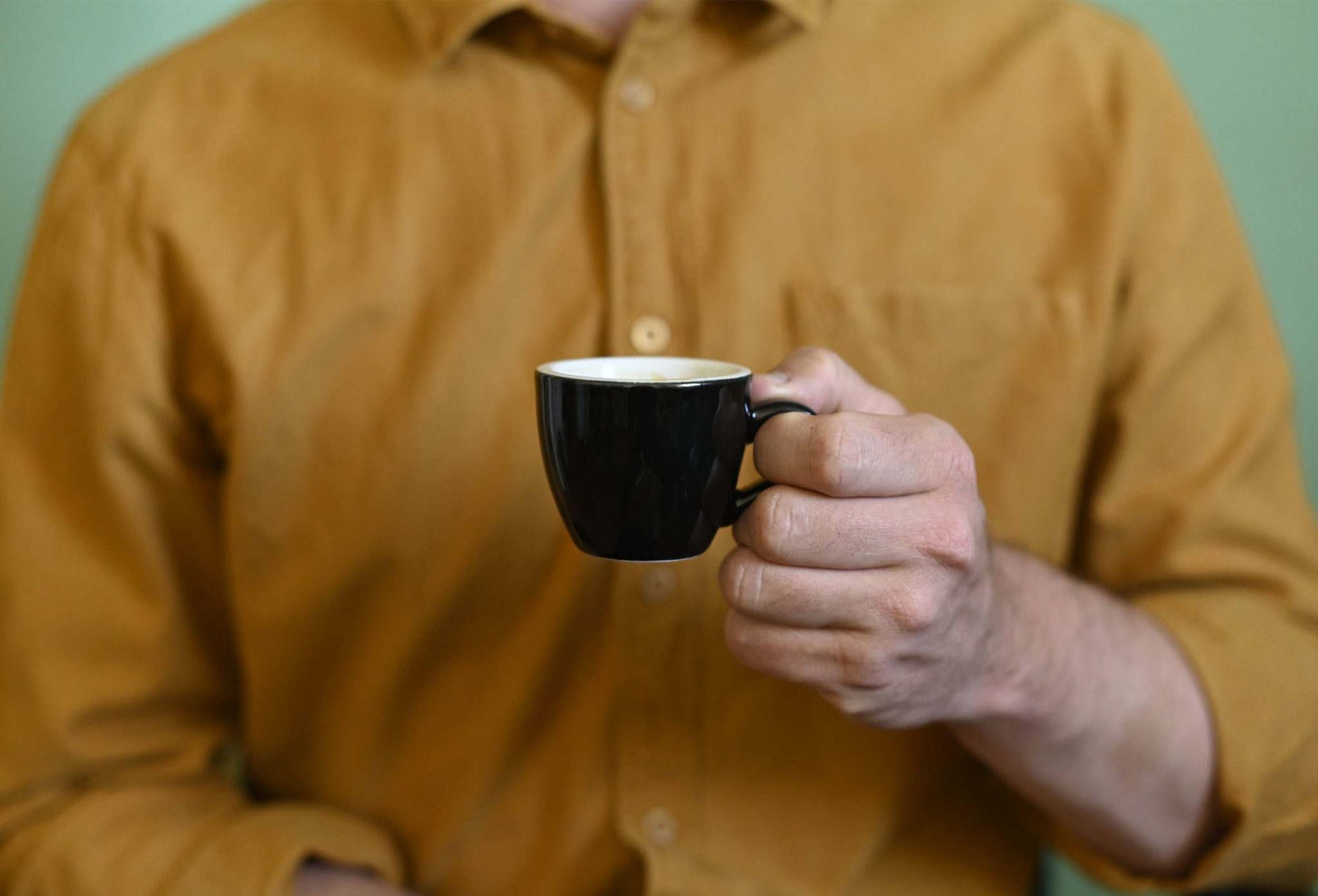 man holding a black espresso cup
