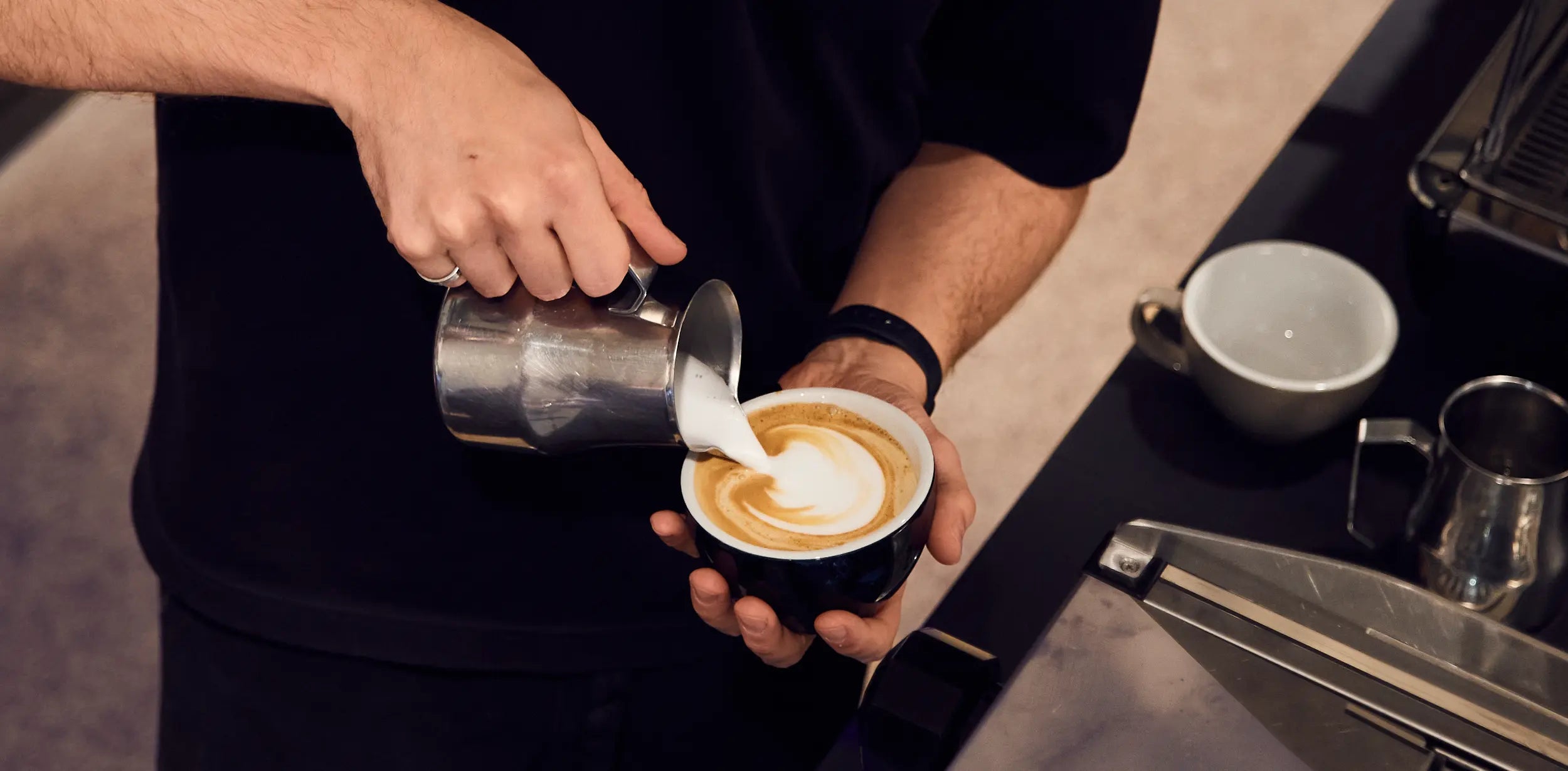 Barista giesst Latte Art in Cappuccino – ViCAFE Latte Art Kurs Gutschein als besonderes Geschenk