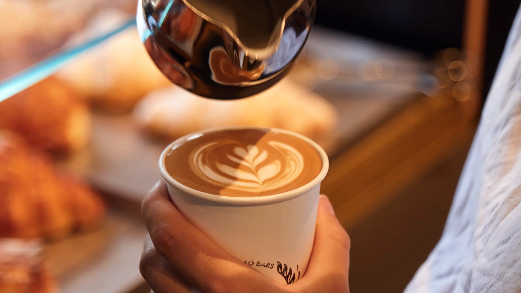Barista giesst feinste Latte Art in einen Cappuccino bei ViCAFE – frisch gerösteter Spezialitätenkaffee aus Zürich, serviert mit Leidenschaft und Präzision.