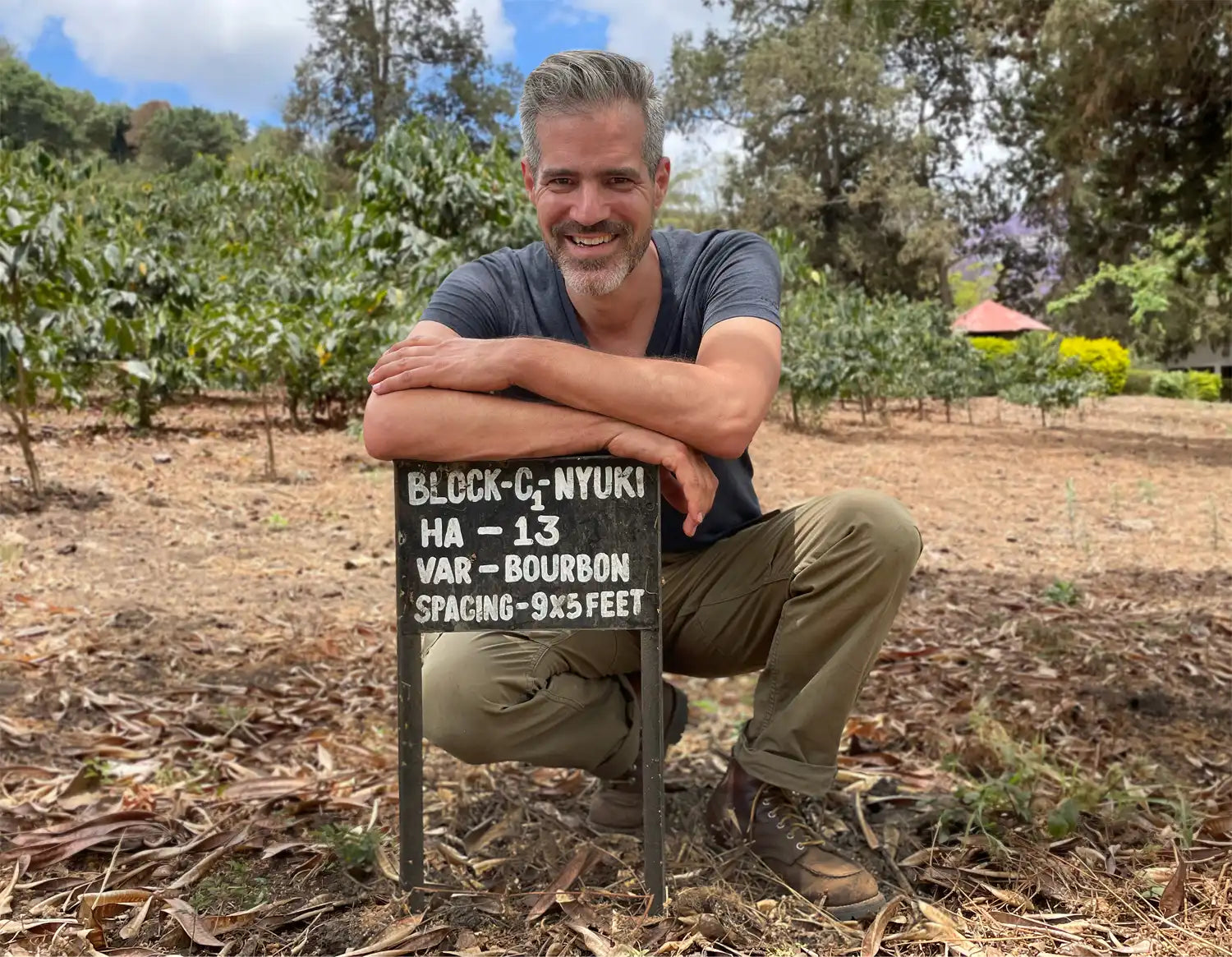 ViCAFE founder posing with a coffee plantation sign on a coffee farm